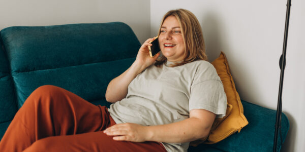 Feature image A young woman lounged on the sofa on a phone.